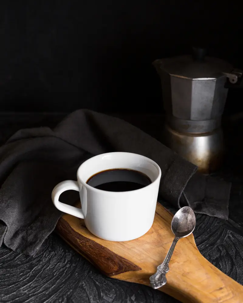 Black coffee in a white mug on a wooden table, symbolizing healthy coffee choices for a weight loss diet plan.